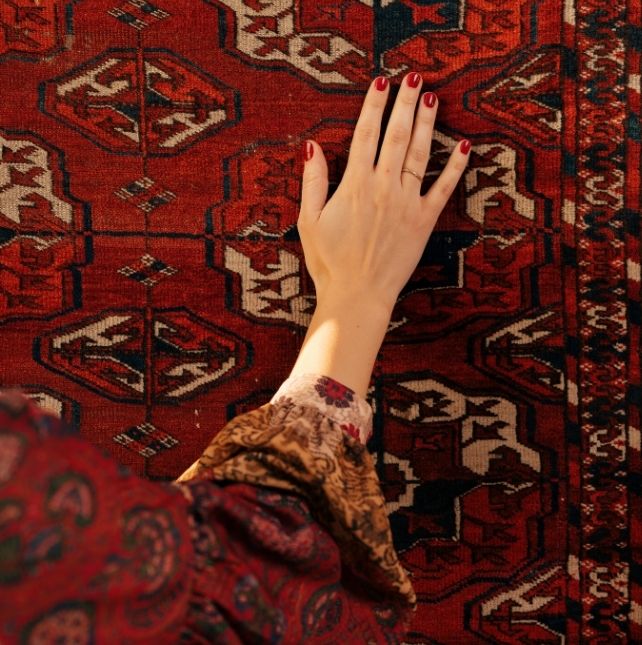 A Turkish girl named Miral Fatima posing gracefully with her hand on a traditional Turkish carpet