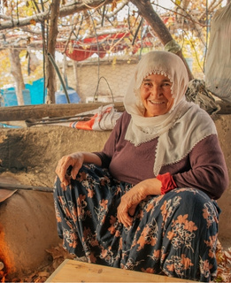 Elderly Turkish woman smiling softly while posing in her traditional home kitchen