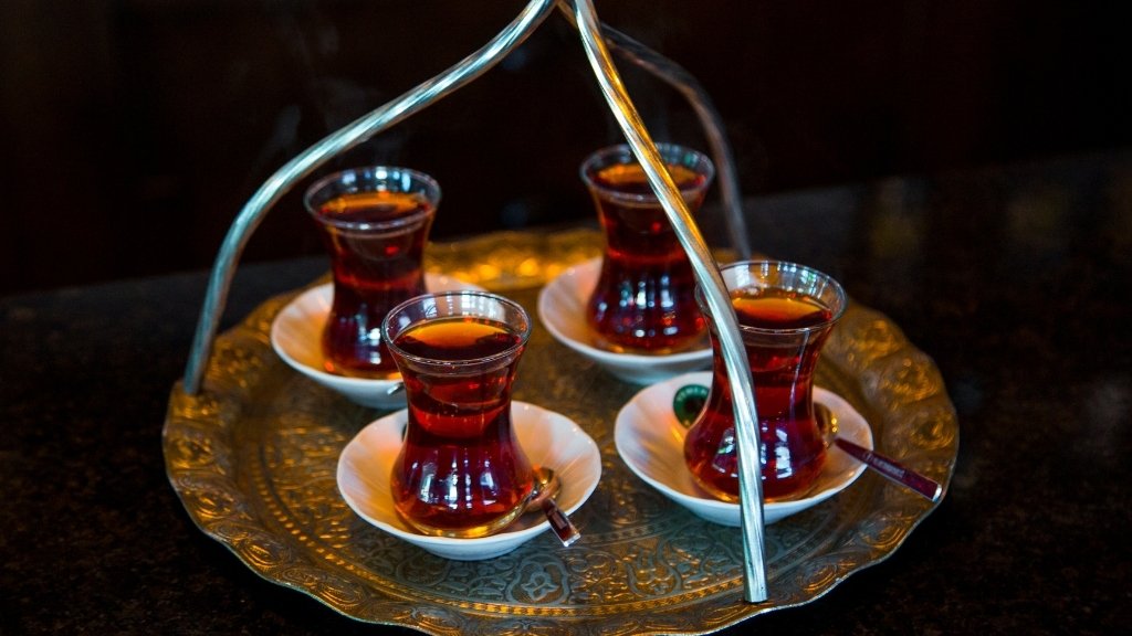 Four steaming glasses of traditional Turkish tea served in tulip-shaped glasses on an ornate tray, symbolizing the warmth and hospitality of Turkish tea culture.