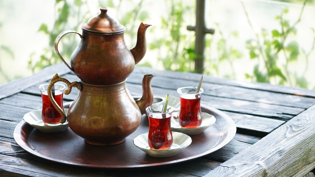 Traditional Turkish çaydanlık with steaming black tea in tulip glasses served outdoors — showcasing authentic Turkish tea brewing and serving ritual