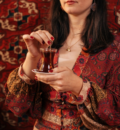 Turkish woman holding a glass of traditional tea in a calm, cultural setting