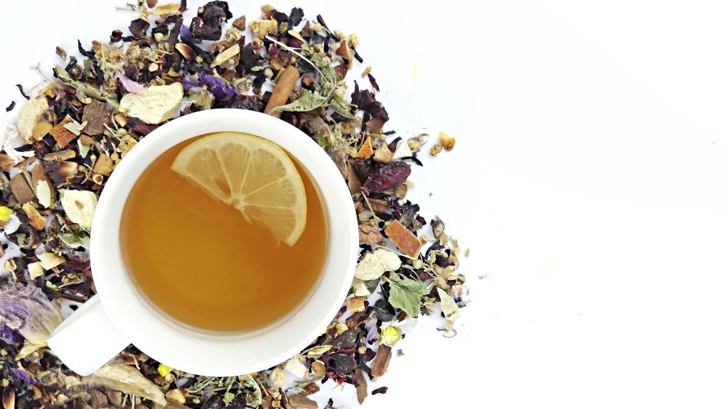 Mixed Turkish herbal tea blend steeping in clear pot, linden, chamomile and sage leaves are besides.