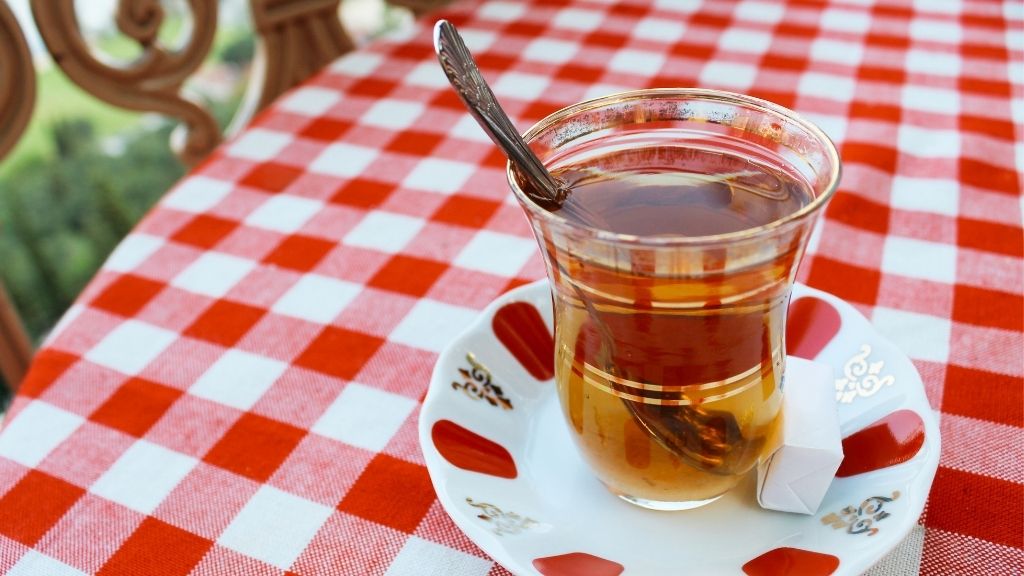 Turkish apple tea, amber brew in tulip glass with sugar cube.