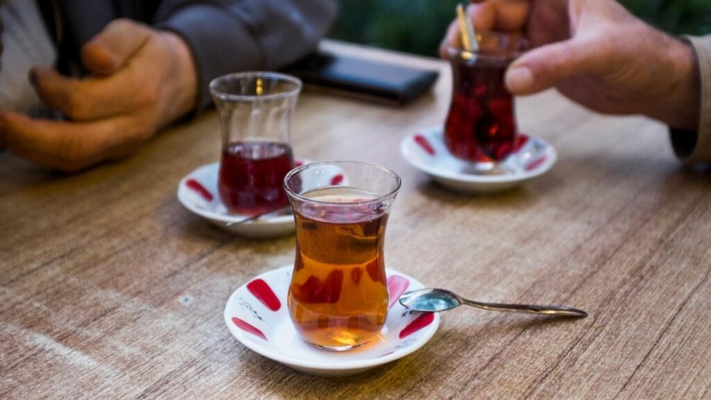 Friends sharing a moment over Turkish Apple Tea and Turkish Tea in traditional curved glasses - a common cultural ritual in Turkish gatherings.