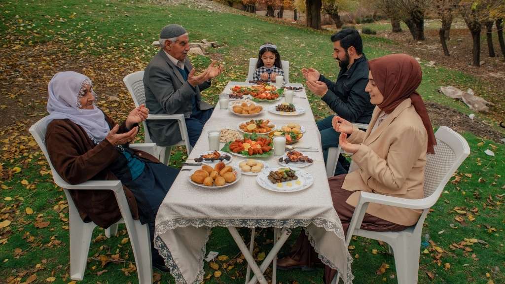 Turkish family sharing traditional meal outdoors, demonstrating dining etiquette in Turkey and cultural customs.